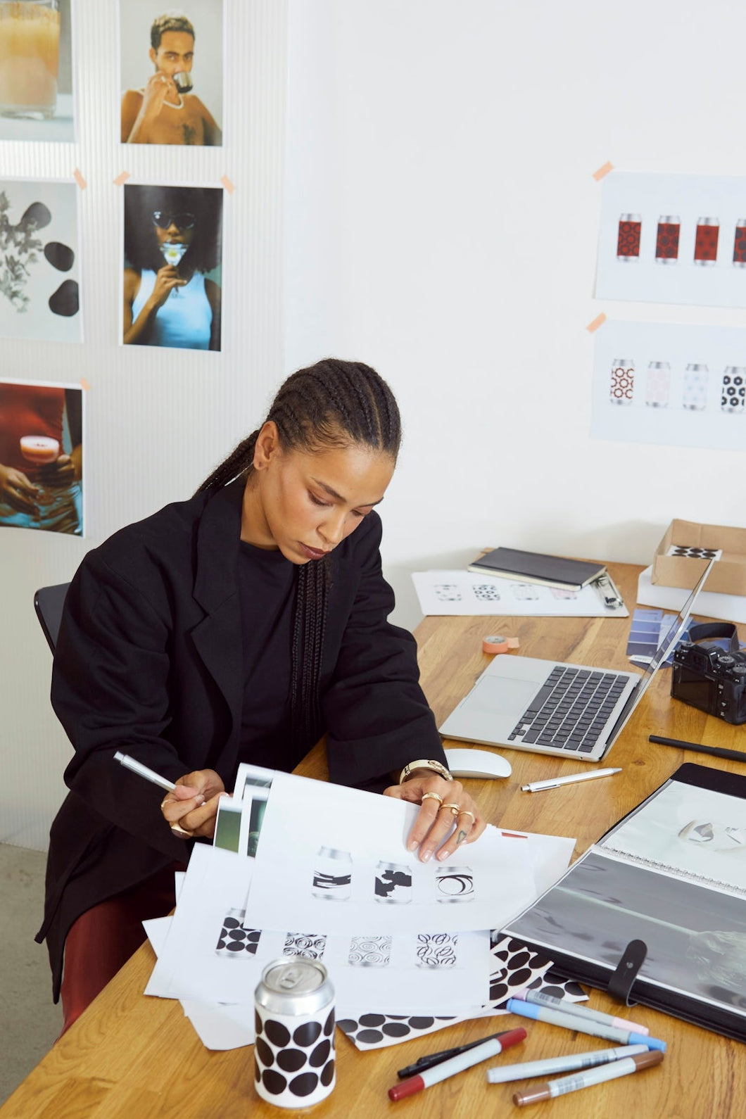 Person sitting at a desk with design materials and a laptop.